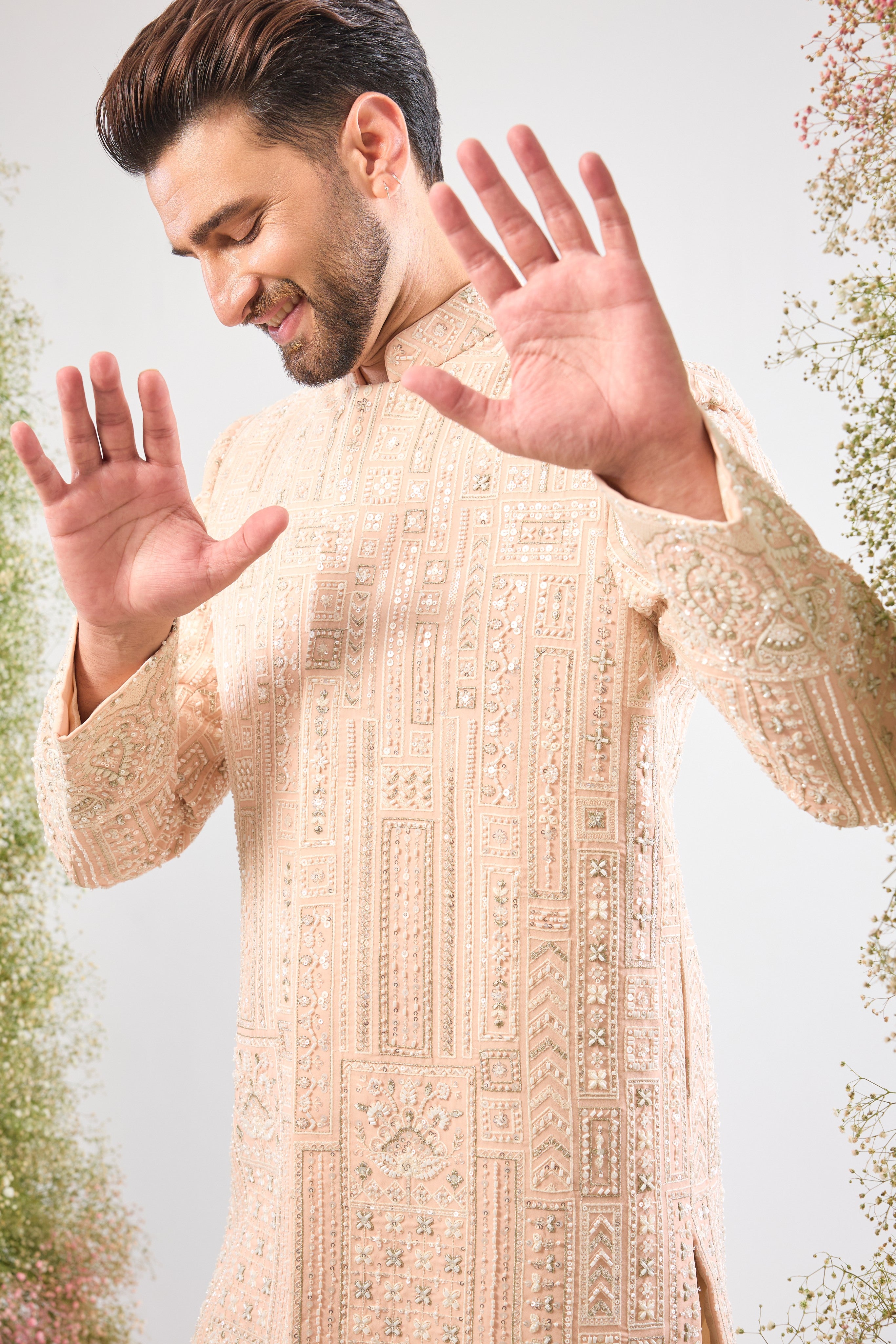 Our Pink Short Sherwani features a striking Geometrically Embroidered pattern, meticulously brought to life with exquisite Hand Work White Cut Dana and Sequin detailing.
