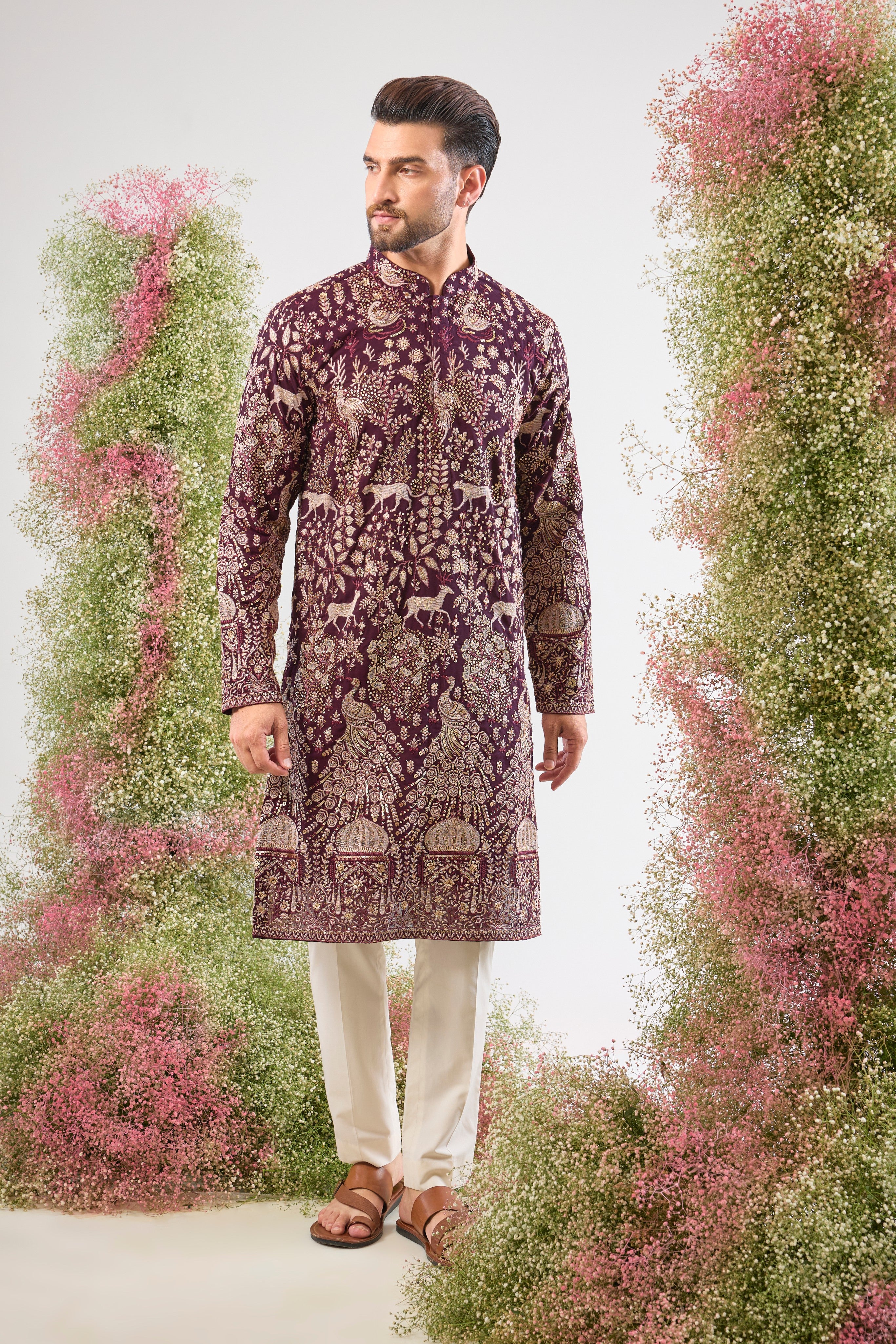 his Wine Long Kurta is super charming and very formal, showcasing intricate Royal Darbars alongside elegant Flora and Fauna motifs, all brought to life by dazzling Zari and Sequin work