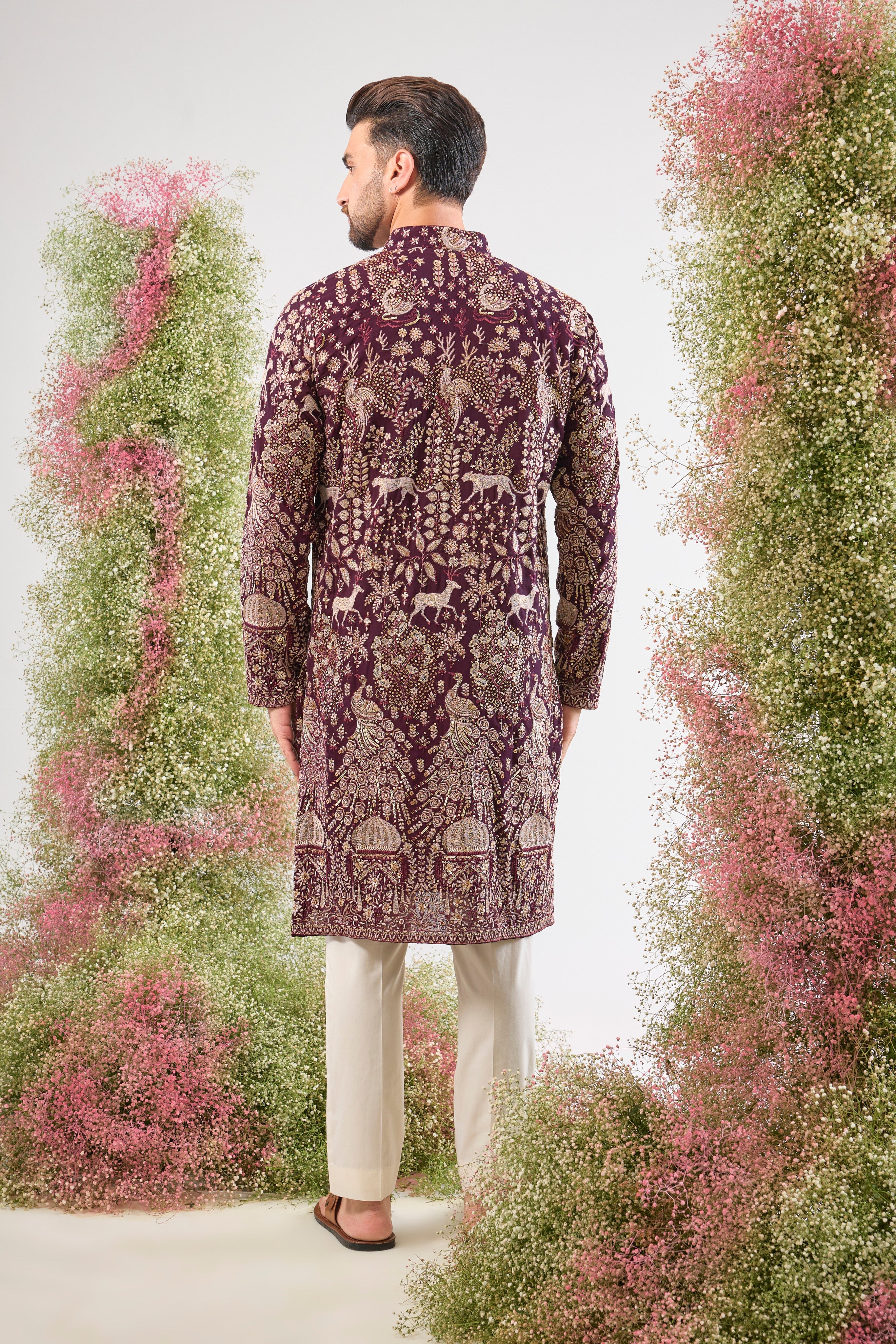 his Wine Long Kurta is super charming and very formal, showcasing intricate Royal Darbars alongside elegant Flora and Fauna motifs, all brought to life by dazzling Zari and Sequin work