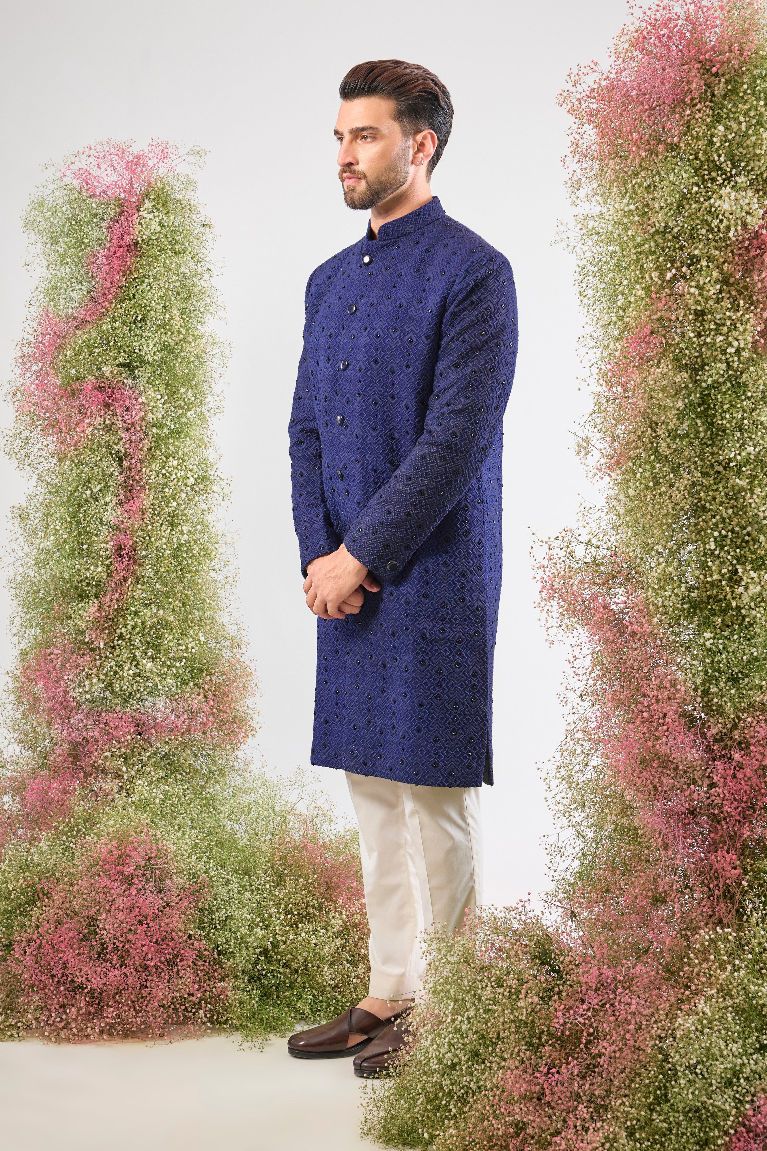 This Sherwani showcases a contemporary Geometrically Embroidered pattern, beautifully contrasted with the subtle, dark sparkle of Hand Embroidered Black Cut Dana.