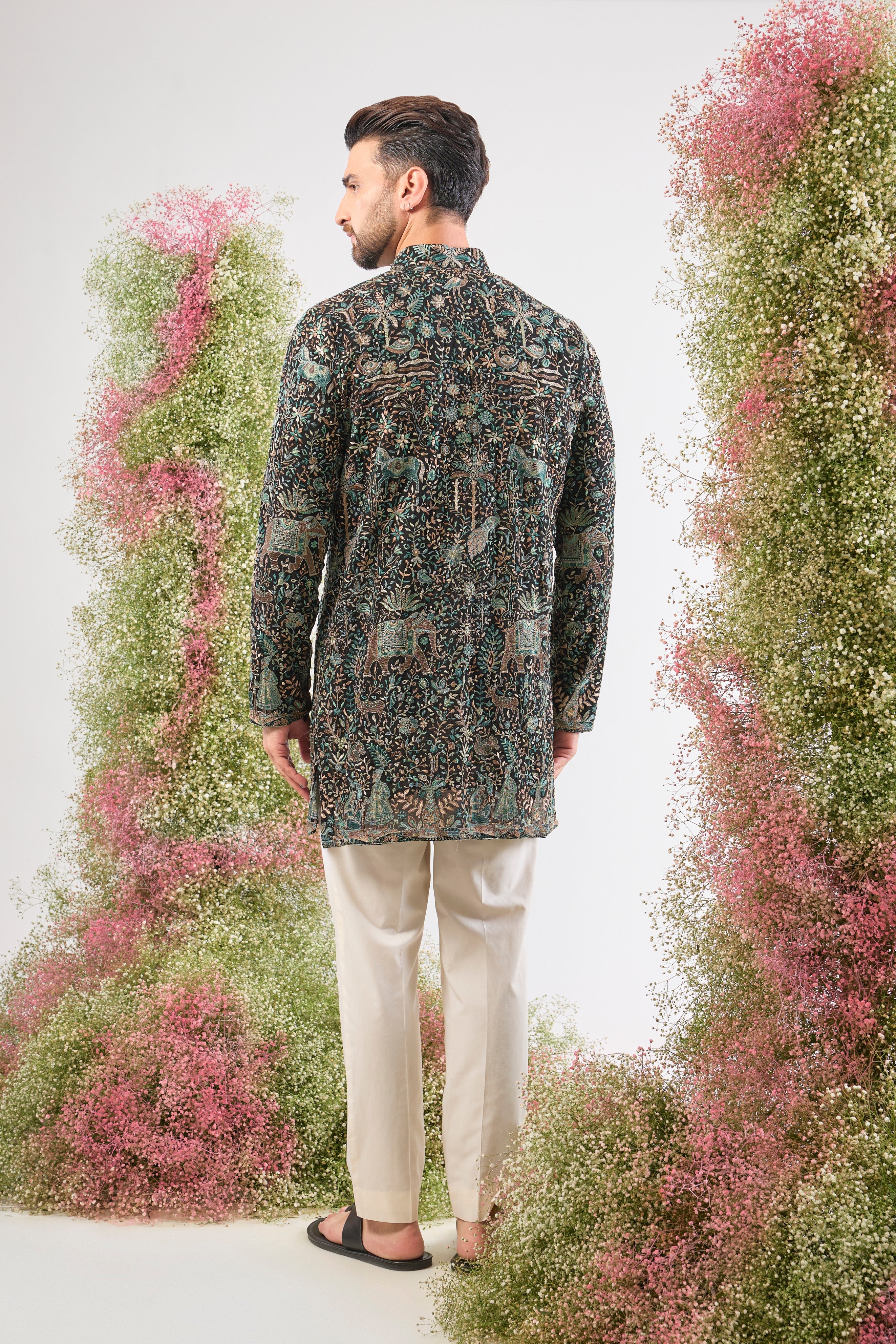 This Black Short Kurta is adorned with rich Kashmiri Embroidery, with every motif showcasing Detailed Flora and Fauna Embroidery. The sequin work provides a beautiful, reflective texture, ensuring a sophisticated and artistic presence at any event.