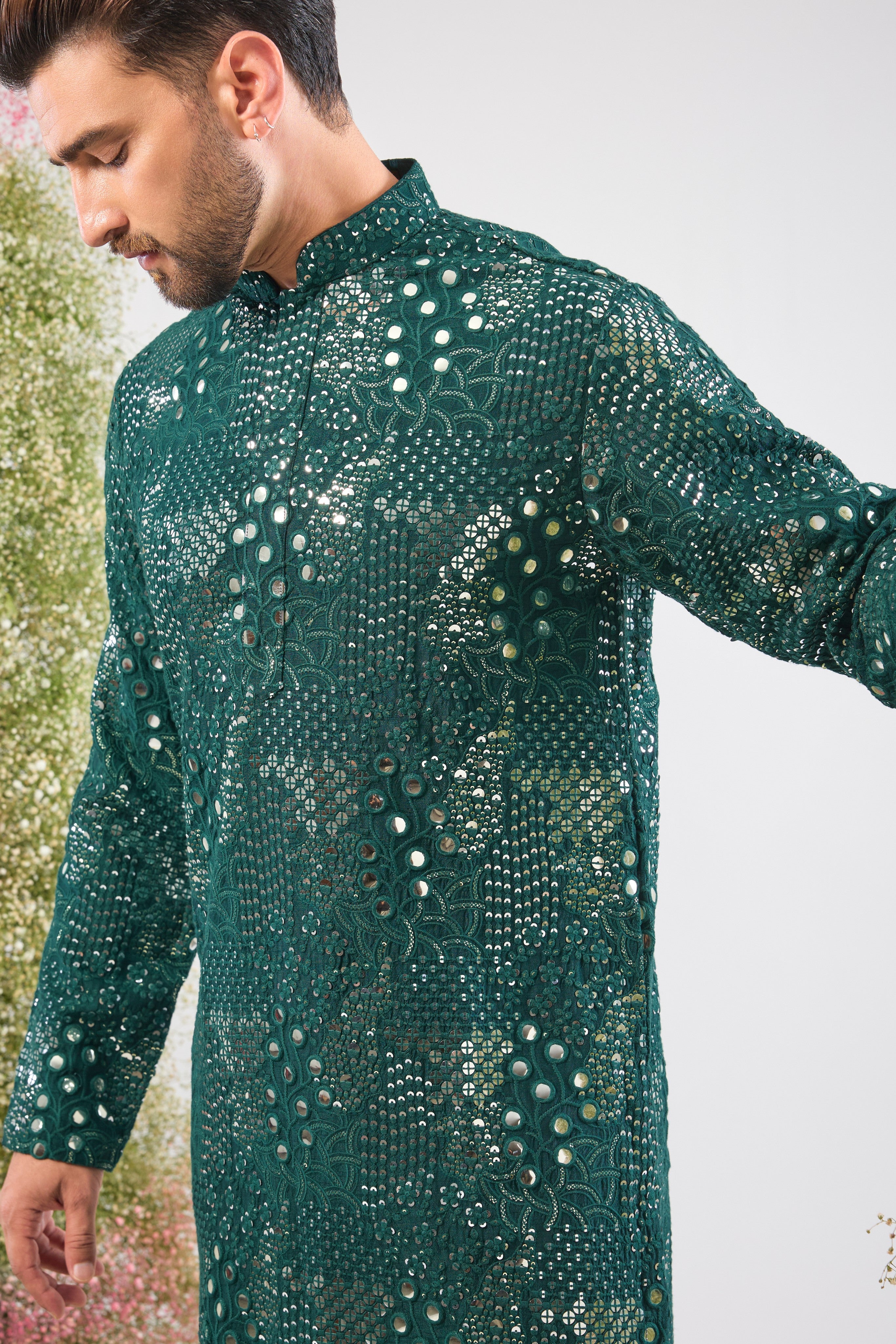This Bottle Green Short Mirror Work Kurta showcases Intricate Sequin Work arranged in a beautiful Floral Pattern. The dense sequin detailing ensures a luminous, unforgettable texture, making it an ideal choice for a sophisticated, festive look.